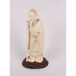 A Japanese carved ivory okimono of a standing figure holding a staff, 7" high