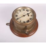 A brass cased bulkhead clock with painted dial on mahogany back plate, 10" dia