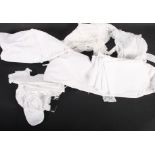 A quantity of baby gowns, dresses and vests, a doll's dress trimmed Valenciennes lace, two