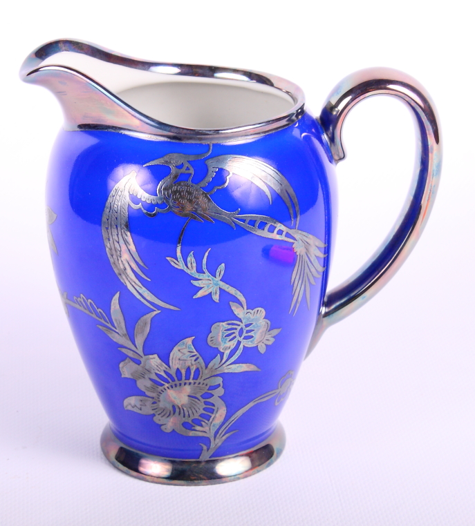 A Rosenthal Chippendale pattern milk jug decorated birds and foliage in silver on a blue ground