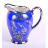 A Rosenthal Chippendale pattern milk jug decorated birds and foliage in silver on a blue ground