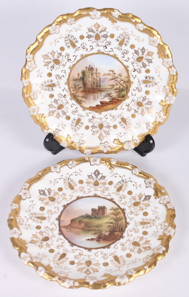 A pair of Coalport wall plates with gilt decorated borders and edges, centres painted named views of