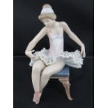 Lladro. A seated ballerina upon four legged stool, standing 15cm high.