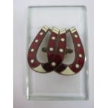 A Victorian glass paperclip in the form of twin enamelled horse shoes on sprung support over
