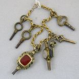 A hollow chain link bracelet seven watch keys attached including a yellow metal repousse key,