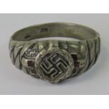 A white metal ring with Swastika surrounded by red enamel; rubbed markings to inside of the band.