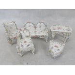 A suite of porcelain dolls furniture including settle, table and chairs. Width of settle 10cm.
