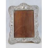 A HM silver repoussse photo frame with four blank cartouches and floral pattern, wooden backing,