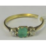 An 18ct three stone emerald and diamond ring, central square emerald approx 0.