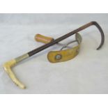 A vintage brass sweat scraper with wooden handle. Together with a horn handled riding crop.