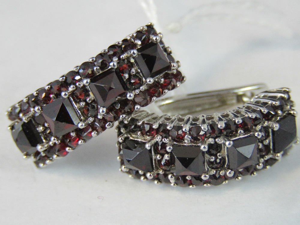 A pair of silver and garnet half hoop ea