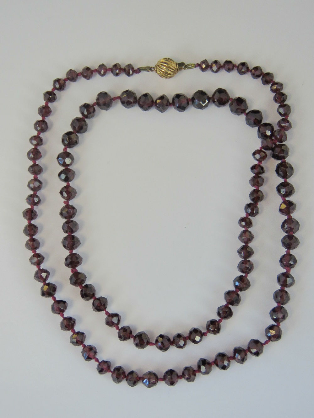 A 9ct gold and faceted garnet bead necklace, 59cm long, clasp stamped 375.