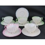 Five Belleek shell designed cups and saucers: three with green edges,