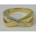 An 18ct gold and diamond ring, three diamonds set in yellow metal crossover design band,