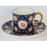A late 19th century Royal Crown Derby coffee can and saucer with pink roses upon a dark blue ground.