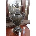 A JAPANESE PATINATED BRONZE URN WITH DRAGON FORM HANDLES AND BASE.