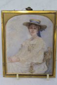 AN EDWARDIAN WATERCOLOUR MINIATURE PORTRAIT OF A SEATED YOUNG LADY WEARING A WHITE DRESS AND SUN