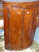 A Regency mahogany and boxwood inlaid bow front corner cabinet