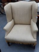 An antique Georgian style wing back armchair of large proportions