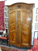 An impressive French provincial fruitwood armoire with carved decoration and applied steel mounts