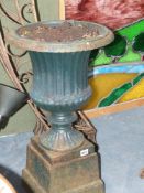 A pair of antique cast iron classical form garden urns on stepped plinth bases