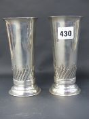 A pair of hallmarked silver tapered form beaker cups with swirled and flared bases