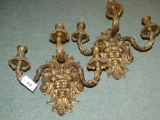 A pair of large French ormolu three branch wall lights with mask decoration in the Regency taste