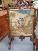 A large and elaborately carved mahogany framed firescreen with fine needlepoint tapestry panel