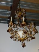 A French gilt metal and alabaster rococo style eight light chandelier hung with prisms and moulded