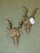 A pair of bronze dolphin form wall lights surmounted by shells and rushes