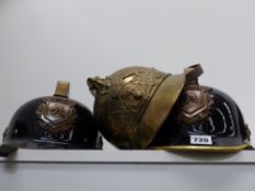 An Antique French brass fire helmet together with two later German examples