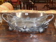 An Art Nouveau silvered chestnut frame oval twin handle centrepiece with cut glass liner