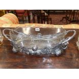 An Art Nouveau silvered chestnut frame oval twin handle centrepiece with cut glass liner