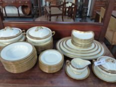 A Royal Doulton part dinner service to include graduated platters, serving dishes etc. Etched gilt