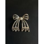 A Belle Epoque all diamond set ribbon bow brooch. With diamond droppers