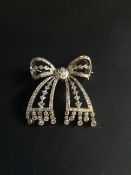 A Belle Epoque all diamond set ribbon bow brooch. With diamond droppers