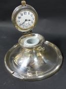 A gentleman's silver desk top capstan inkwell. The lid incorporating a timepiece. dates Birmingham