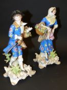 A pair of Continental porcelain figurines. Depicting a man and woman holding baskets of flowers