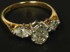 An 18ct gold three stone diamond ring. The centre oval cut diamond flanked by two marquis cut