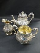 A Victorian silver three piece tea set. Decorated with repousse flower heads in cartouches. London