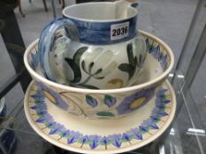 Three pieces of Wedgwood pottery, a studio jug with stylized flowers, a deep bowl and a charger in