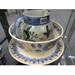 Three pieces of Wedgwood pottery, a studio jug with stylized flowers, a deep bowl and a charger in