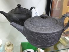 Two black Basalt Wedgwood teapots one of round squat form with classical figures, the other oval