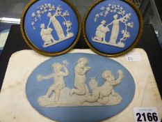 An antique oval blue jasperware plaque of playful putti mounted on a white marble slab and a pair of