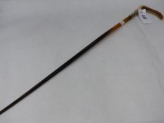 A LARGE RHINO HORN RIDING CROP WITH WHITE METAL MOUNTS AND ANTLER HANDLE.