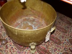 A LARGE ANTIQUE BRASS LOG BIN ON CAST PAW FEET.