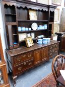 A 19TH.C.OAK AND MAHOGANY CROSS BANDED DRESSER WITH ARRANGEMENT OF DRAWERS AND DOORS ON SHAPED