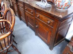 A LARGE EARLY 19TH.C.OAK INVERTED BREAKFRONT DRESSER WITH FOUR DRAWERS OVER PANELLED DOORS. 245cms