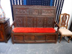 AN 18TH.C.OAK BOX SEAT HALL SETTLE WITH SEVEN CARVED PANELS TO THE BACK AND PLAIN PANELLED FRONT.