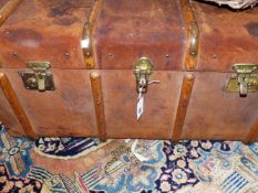 A LARGE WOOD BOUND LEATHER TRAVELLING TRUNK.